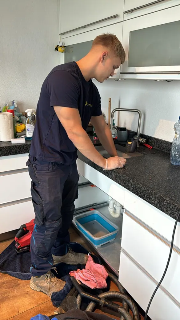 Monteur controleert en ontstopt een keukenafvoer onder de gootsteen