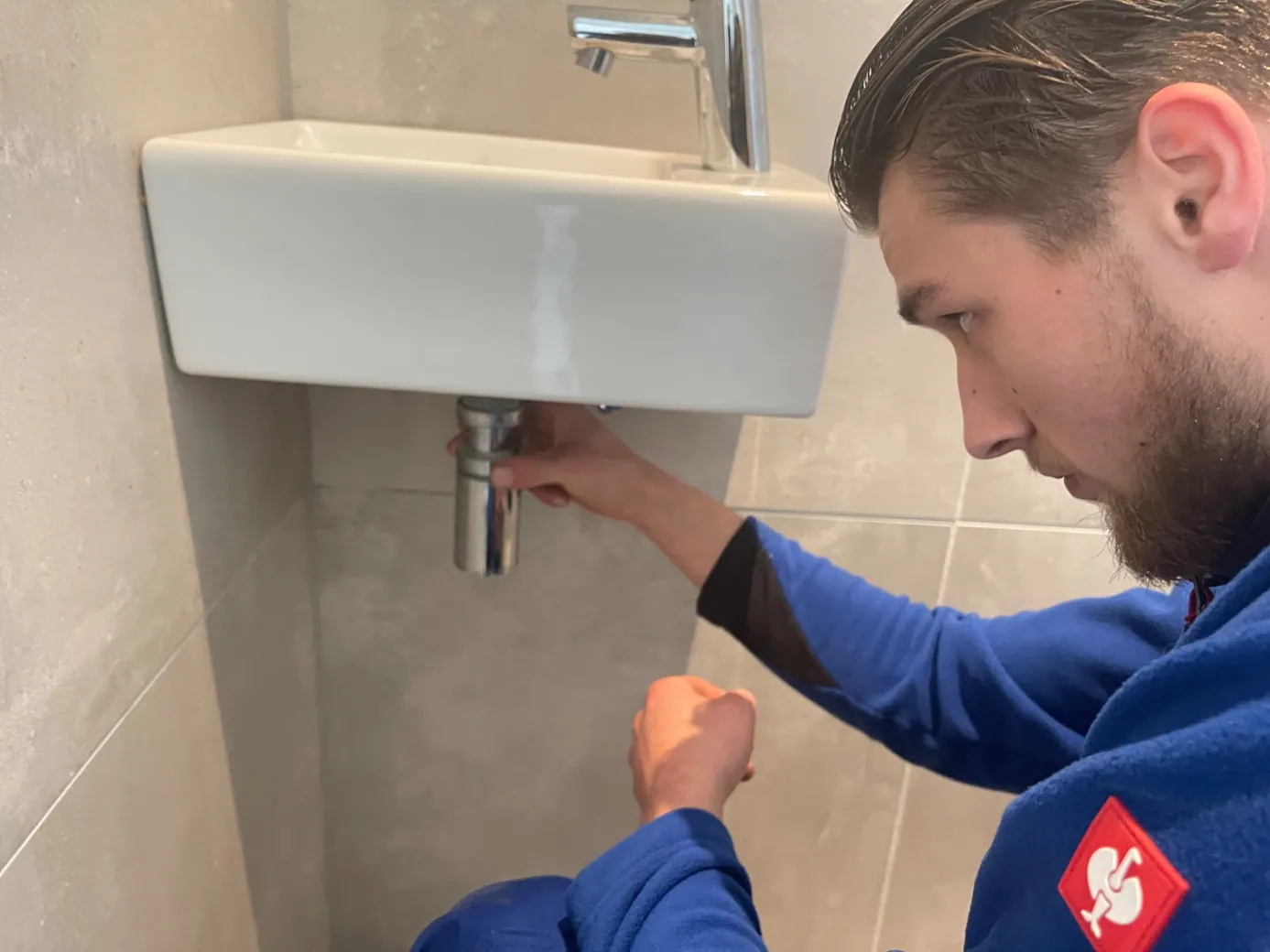Monteur inspecteert een wastafelafvoer en sifon - praktijkbeeld