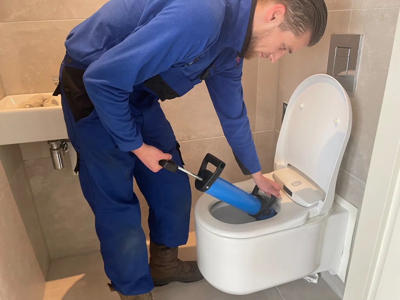 Monteur ontstopt een verstopte wc met professionele apparatuur - praktijkbeeld
